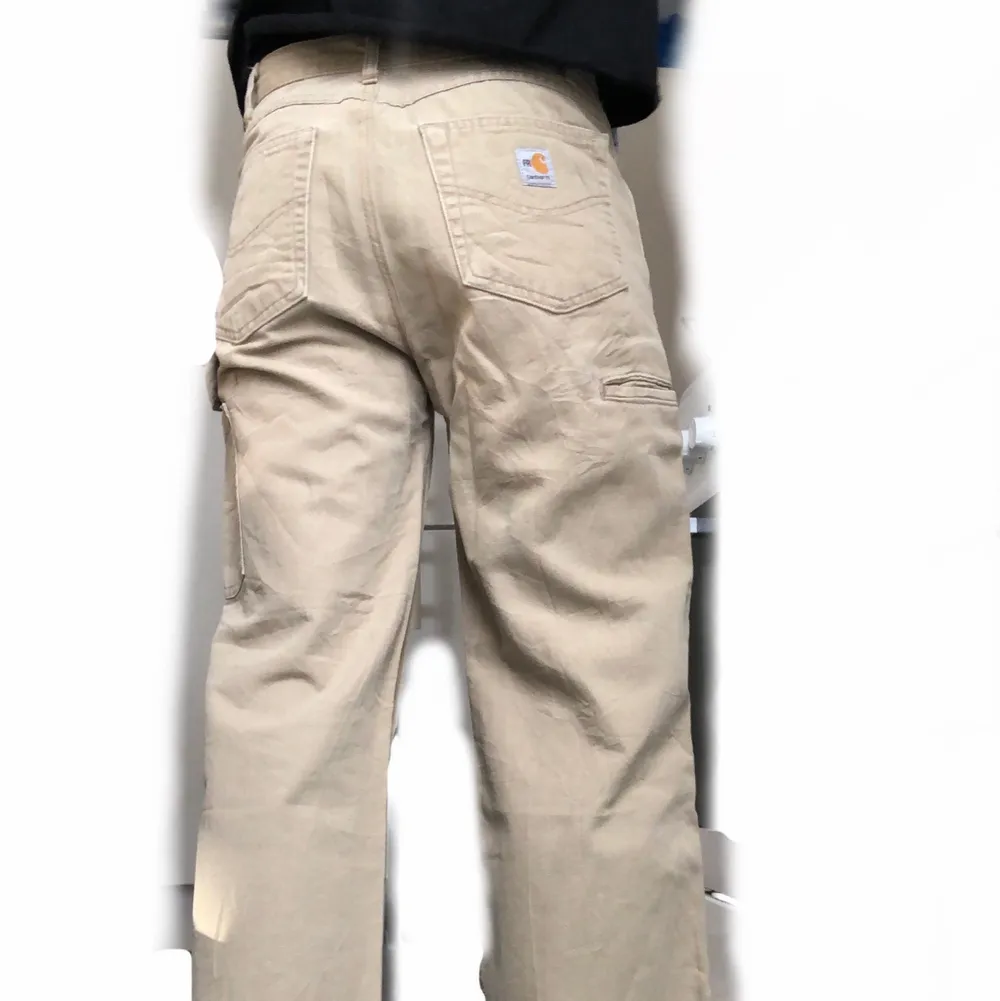 Säljer ett par beigea Carhartt Workpants, köpta second hand. Oklar storlek, men känns som (W30) Avklippta i benen! Lite frakt tillkommer☀️. Jeans & Byxor.