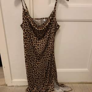 Snygg leopard klänning i glansigt material och liten slitts