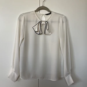 Vit blus med rosett  - Söt vit blus med rosett från Zara i storlek S. Den är i fint skick och har ett fint fall. 