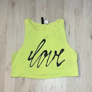 En neongrön topp med ett stort tryck på framsidan där det står ”Love” från H&M i bra skick då den inte har kommit till användning☺️
