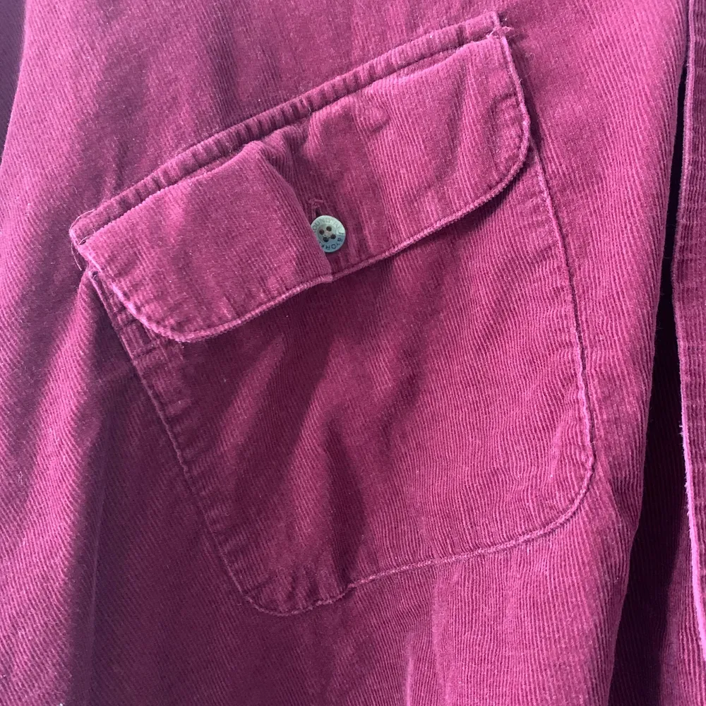 En supersnygg croppad skjorta i färgen ”burgundy”. Tröjan är köpt i vintage butiken ”ATIKA” i London och saknar tyvärr en knapp på ena fickan som sitter på bröstet. Skjortan har en oversized passform (skulle gissa på storlek L). Köparen står för eventuell frakt. . Skjortor.