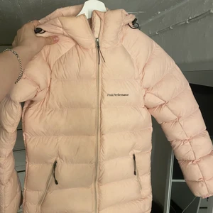 Peak Performance jacka - Ljus/smuts rosa peak performance jacka i dun,  strl XS. Ljuset gör inte färgen riktigt rättvis. Jag har normalt XS men denna skulle jag säga är mer som en S/M, fungerar bra på mig som har ganska långa armar. Använd max 5 ggr och inköpt i vintras. Nypris 1999kr, pris kan diskuteras vid snabb affär.