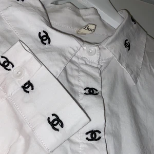 Chanel Skjorta - En vit skjorta med chanel mönster på sig. Den har en mindre fläck på sig på baksidan. Är i desperat behov av att bli struken. 264 = 4 ciggpaket + frakt = 323 kr