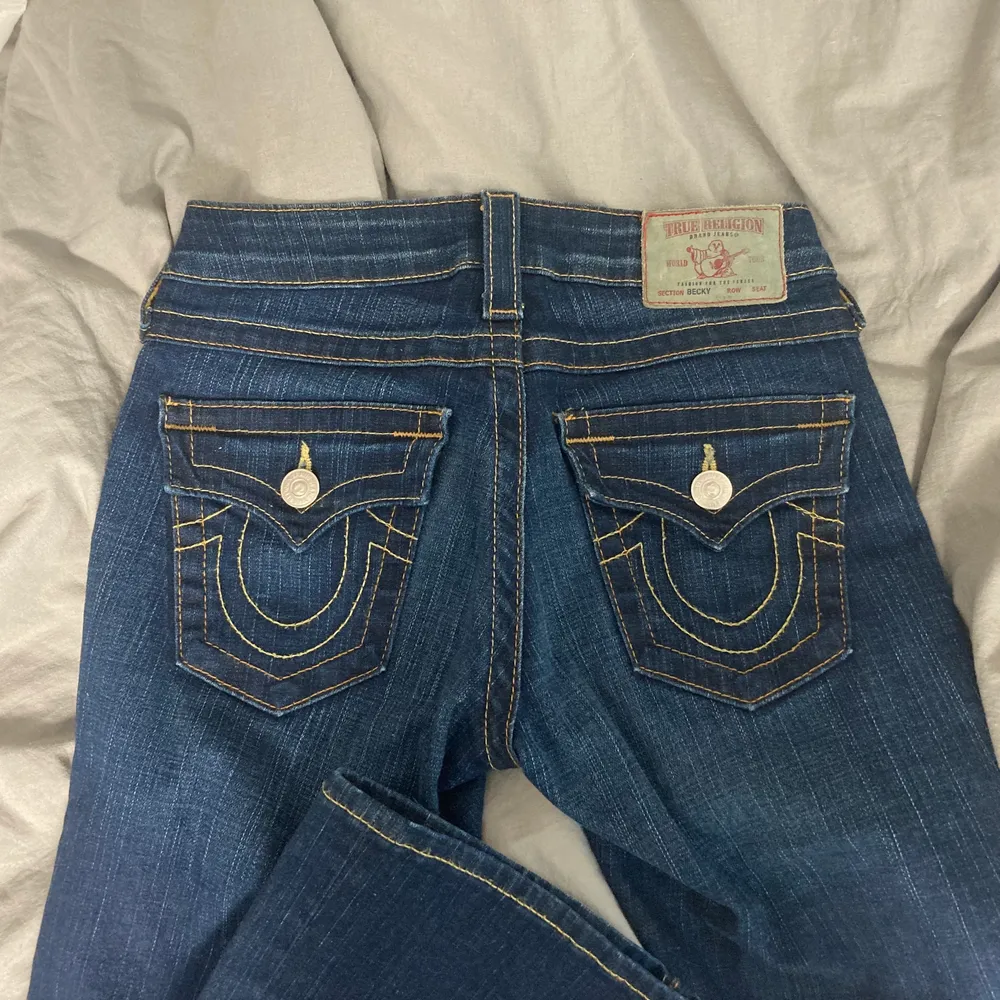 Säljer ett par jättesnygga lowwaisted jeans från True Religion i modellen ”Becky” som tyvärr inte har kommit till använding då de är förlånga för mig (jag är 155cm). Innerbenslängden är 85cm och de är stretchiga i materialet. Inga defekter förutom att dragkedjan är förstörd på ett ställe (som inte syns då det är på insidan) men den går att dra upp och ner ändå! Skriv för mer info❤️. Jeans & Byxor.