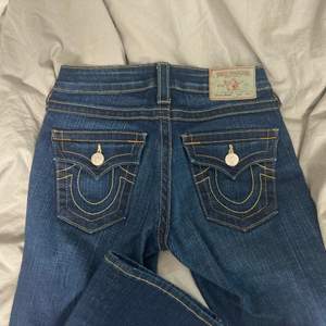 Säljer ett par jättesnygga lowwaisted jeans från True Religion i modellen ”Becky” som tyvärr inte har kommit till använding då de är förlånga för mig (jag är 155cm). Innerbenslängden är 85cm och de är stretchiga i materialet. Inga defekter förutom att dragkedjan är förstörd på ett ställe (som inte syns då det är på insidan) men den går att dra upp och ner ändå! Skriv för mer info❤️