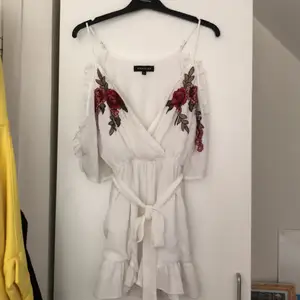 Vit Playsuit i stl S. Broderade blommor på.                    - Trekvartsärm med öppning i axeln.                                   - Band som går att ta av finns även.                                    - Bra skick.                          