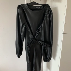 Skinnkläning - Svart skinnkläning från ginatricot med avtagbart snöre som ska knytas i midjan. Använd ett fåtal gånger. 