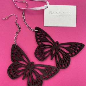 Fjärlisörhängen - Ett par fina fjärilsörhängen i brun mocka från märker plain vanilla. Aldrig använda! Orginalpris: 300 kr, säljer för 50 kr. Fraktkostnad tillkommer💚