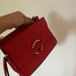 Röd väska med guldiga detaljer från Mango.