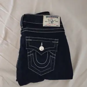Snygga mörkblå jeans från True Religion med special fickor och pärlor, storlek 28 Innerbenslängd: 80 cm Ytterbenslängd: 101.5 cm Midjemått: 38 cm
