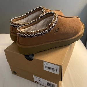UGG tasman  - Jag säljer mina oanvända UGG tasman i färgen chestnut. De är inköpa i september, men har aldrig kommit till användning. Nypris 1499kr. 