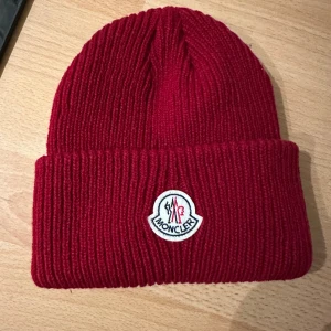 Monclear mössa / Röd ny med tags!  - Ny mössa från märket Monclear. Inköpt på Vinted. Hör av dig om du önskar mer bilder. Pris kan diskuteras, men vill helst inte gå ner allt för mycket i pris då jag har köpt den dyrt! 