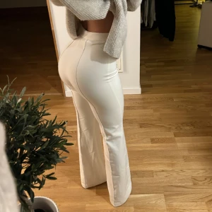 Kostymbyxor UK 4 - Högmidjade kostymbyxor från Ohpolly i strl UK 4 US 0. Färgen är lite krämvit. För referens är jag 167cm lång och dessa går hela vägen till marken på mig. Finns tecken på användning. Se bild 3.