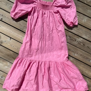 Klänning rosa  - Drömklänningen från H&M storlek S En rosa smällkaramell med puffärmar  Long, A-line dress in a crisp organic cotton weave with smocking at the top. Square neckline with concealed elastication to keep the dress in place and wide, half-length sleeves 