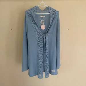 Ljusblå stickad kofta från Odd Molly - En ljusblå stickad kofta från Odd Molly med virkade detaljer runt halsen och framkanten. Koftan har långa ärmar och knytband framtill. -Material: 100% bomull -Storlek: Medium Mått- Längd: 83cm Axlar38c Byst: 42 Ärm:52 Skick: Ny med tags