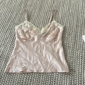 Söt topp - Söt topp från Åhléns, i ett satin liknade material med spets på💕jätte fin ljusrosa färg med justerbara band💕knappt använt så bra skick💕💕💕