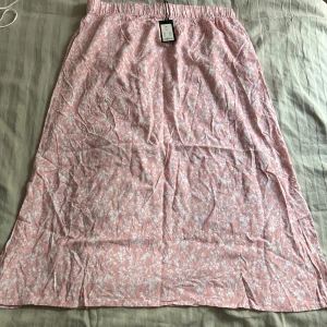 Söt blommig kjol - En fin rosa kjol med vitt blommigt mönster. Storlek XL. Oanvänd. 