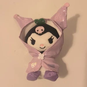 Kuromi Raincoat Plush - Litet plush men regnjacka. Man kan ta av regnjackan och då använda den som nyckelring, annars är det mer ett litet gosse. Riktigt sanrio! ca 14cm