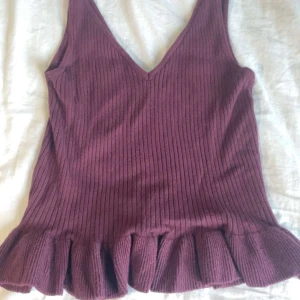 Mörk lila blus - En mörk lila V-blus med volanger nederst, använd 2 gånger.