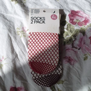 2 pack fishnet strumpor rödlila - Två par fishnet strumpur i två olika färger från H&M. Båda lutar åt det lite rödlila/vinröda hållet färgnässigt, skulle jag säga.Onsize! Helt oöppnade och oanvända! Nypris 79.90!