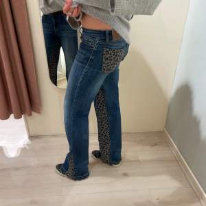 Blå egengjorda jeans med låg midja och utsvängda ben. Leopard tyg på båda sidor och bakfickorna. Midja: 37cm. Innerben: 82cm
