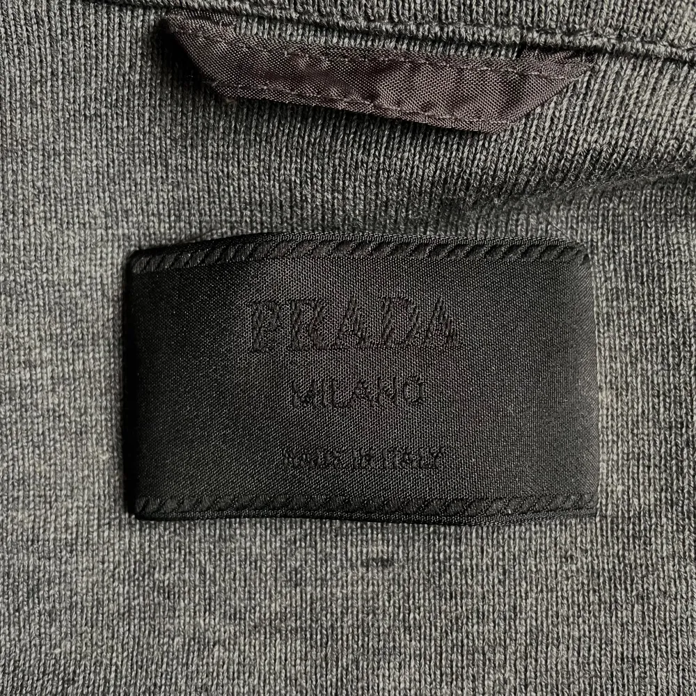 Beautiful Vintage Prada Milano Cotton Knit Zip Sweater Jacket in Grey.  Silver colored metal hardware with embossed “Prada Milano”.  1 Top Zip and 2 Side Zip Pockets + a  drawstring feature for an adjustable waist. Some yellowing around shoulders . Tröjor & Koftor.