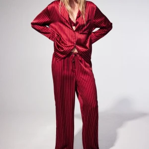 Satinpyjamas med skjorta och byxor  - Pyjamas med skjorta och byxor, följsam satin. Byxor med resår och dragsko i midjan, skjorta med knäppning fram.  Material: 100% polyester, maskintvätt 