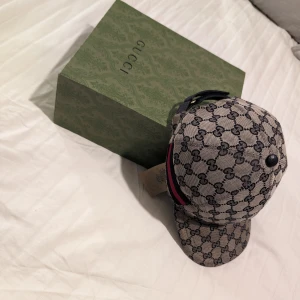 Gucci keps  - Gucci keps 9/10 i skick, använd men ser ändå väldigt fräsch ut. Finns kvitto och även ordinarie förpackning. Storlek XS men går att justera och de är stor i storlekarna. Ny pris 4600