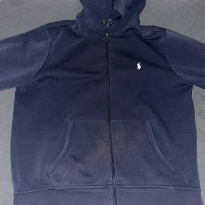 Polo Ralph Lauren zip - Skön Ralph Lauren zip utan hål. Den har en liten grön färg färgfläck på ena armen som säkert går att tvätta bort och tappat lite färg vid fickorna. Annars är den i ett fint skick utan några hål, snören kan läggas till.