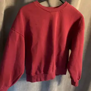 En vanlig tjocktröja med en jättefin röd färg! Tyvärr är det en liten fläck som ej går bort men generellt är tröjan i bra skick! 