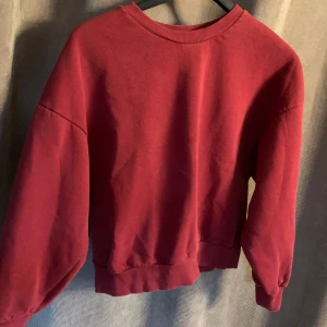 Vinröd tröja - En vanlig tjocktröja med en jättefin röd färg! Tyvärr är det en liten fläck som ej går bort men generellt är tröjan i bra skick! 