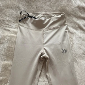 Beiga träningstighta - Beiga träningstights från lager157. Material som andas och som snabbtorkas. Har aldrig används. Snörning i midjan. 