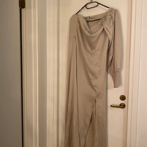 Balklänning - Champangefärgad balklänning med en arm och slits vid benet. Otroligt fin och endast använd en gång. 