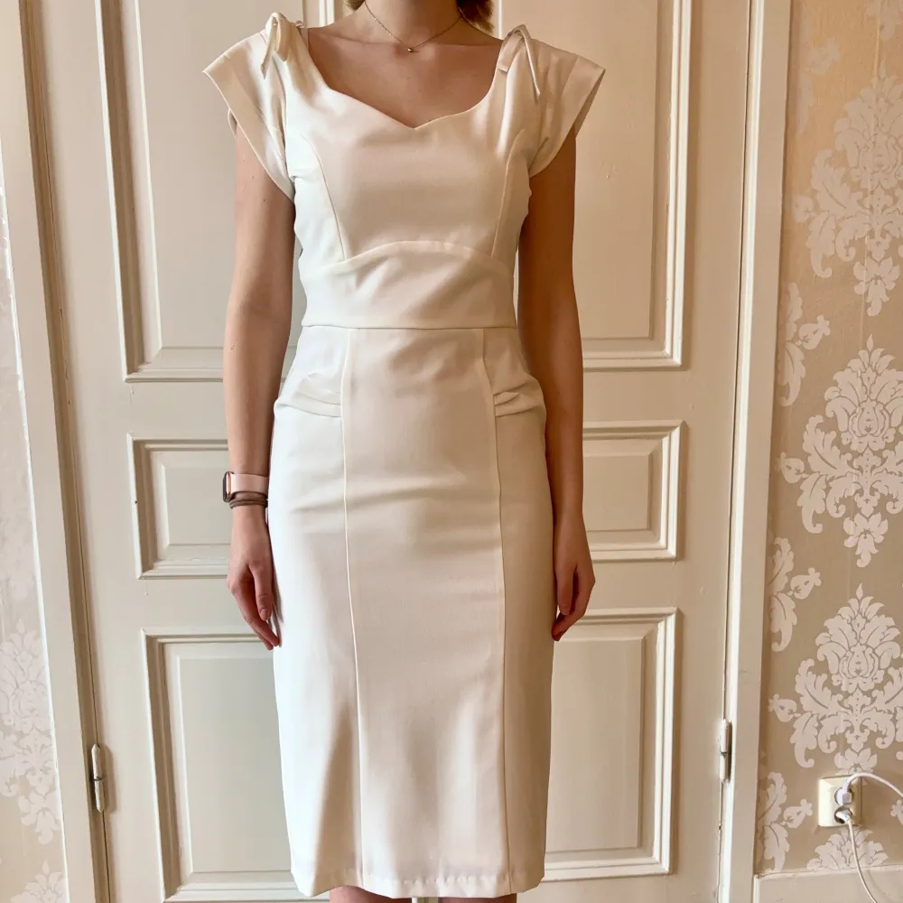 Jättefin vit klänning med två rosetter  i skönt material. Storlek M.  Modellen på bilden är 173 cm och har storlek 38 i de flesta andra kläder. Aldrig använd. Vi har lagt ner vår klänningsbutik och säljer ut. Ny pris är 2000-3000kr. Klänningar.