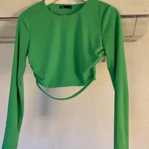 Grön topp från Zara med långa ärmar, dragkedja på axeln att försluts med samt öppen rygg med två band. Använd en gång.