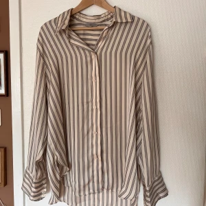 Randig skjorta i silke  - Randig beige skjorta i nyskick 🌼 Materialet är silkesaktigt och tunt. Stl M från HM. Endast använd få gånger.