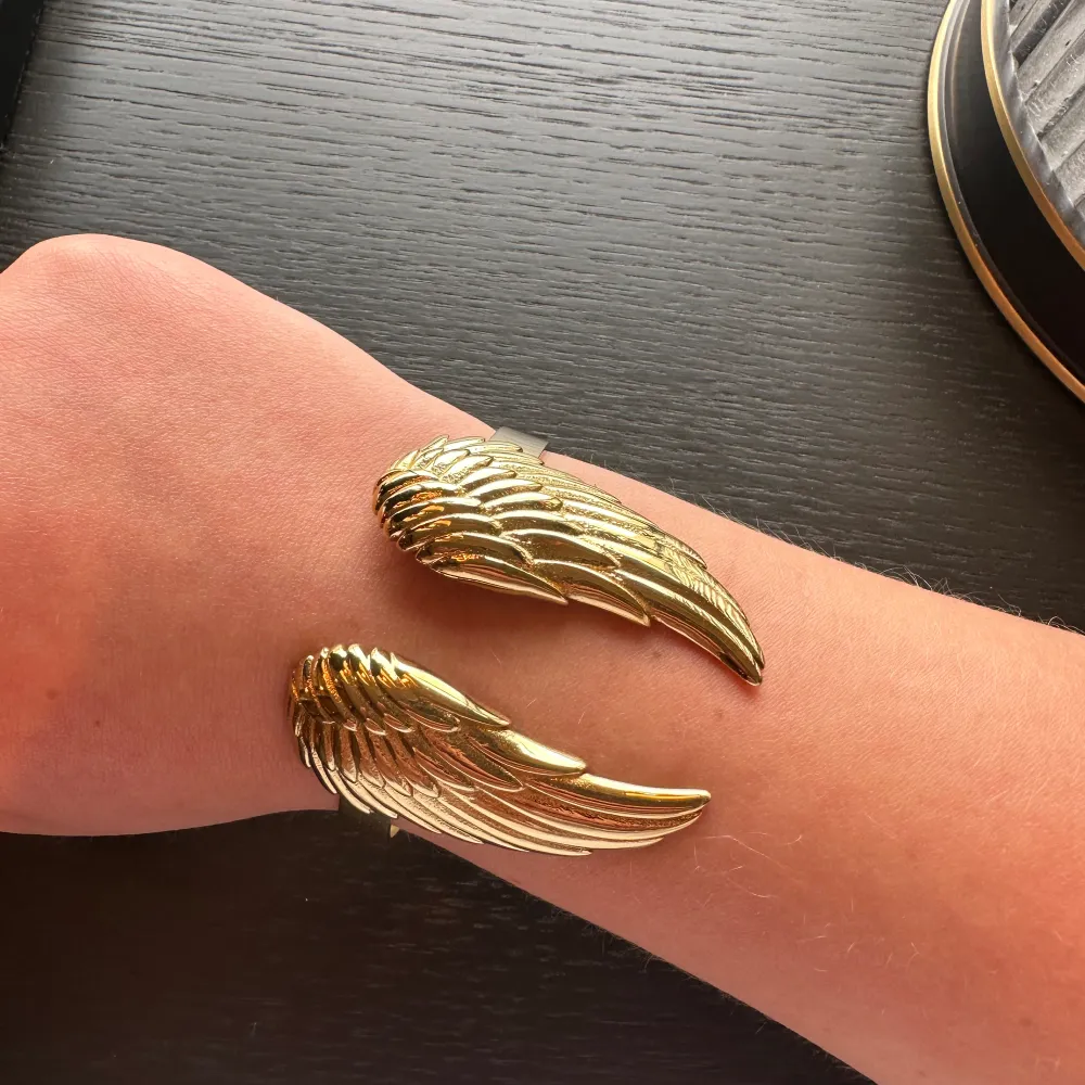 Superfint guldigt justerbart armband med änglavingar. Armbandet är köpt på Edblad och är fortfarande i nyskick. Jag säljer det pga att det inte kommit till användning🩷.. Accessoarer.