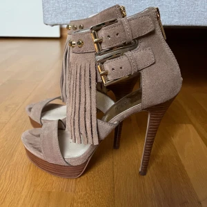 Michael kors klackskor  - Michael Kors klackskor i brun mocka med fransar. Endast använda 1 gång Storlek 37