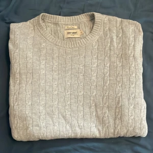 Kabelstickad tröja  - En grå Kabelstickad tröja från East west. Tröjan är i utmärkt skick och har inga hål eller andra defekter. Storlek medium.  Hör av dig för fler bilder eller frågor!