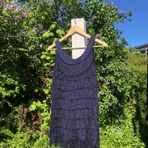 Mörkblå kort klänning med tassles på från HM, mjukt och stretchigt material som funkar för xxs-m