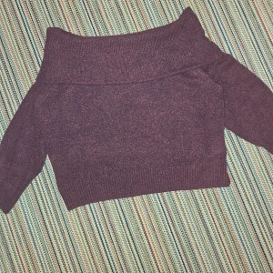 Stickad tröja med axlarna blottade. - Tröjan är mjuk och sitter på armarna så axlarna är fria. Den är röd-lila.