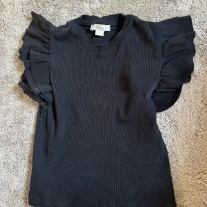 Gullig topp - En svart topp med volangarmar, ifrån Gina Tricot. Barnstorlek 134-140.  Använd typ en gång, säljer då den inte kommer till användning.  Tvättas innan postningen, priset kan diskuteras. 
