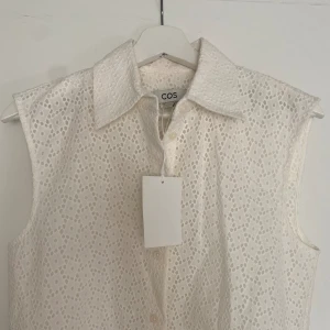 Oanvänd klänning från COS - Ny, har lapp kvar! Nypris 1200kr! Fin bomullspets med foder.  Rak modell men fint fall. Även fin med skärp i midjan.  Säljer pga lite för liten. Är storlek 32 men skulle säga att den är som en XS eller 34 (cos är stora i storleken)