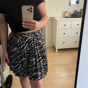 Kjol med mönster - Kort kjol med veck. ”Zebra” mönster. Är som ”shorts” under. Använd fåtal gånger. Ganska liten i storlek upplever jag💕