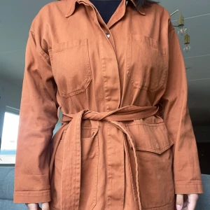 Vårkappa  - En tegelröd kappa som är köpt från monki för några år sedan. Det har ett band runt midjan som man kan ta bort om man vill🫶🏻