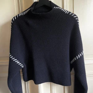 Stickad tröja Hm Premium Selection - En tröja i mjuk ribbstickad ull med kontrastfärgad vita sömmar. Den har långa ärmar & är lite kortare på längden.  Från Hm premium selection. Super fint skick endast använd 1 gång.