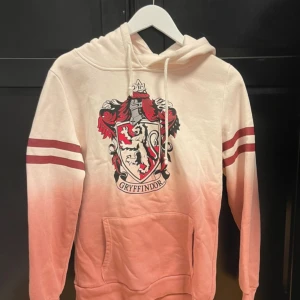 Hoodie - Rosa Harry Potter hoodie. Griffindor. Den är köpt för 600kr och är använd 2-3 gånger. Den är super fin och i rejält bra skick. Den är i bra kvalitet och är mjuk och gosig inuti