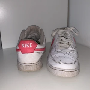 Nike skor  - Vita Nike skor med rosa nikemärke. Skorna är i bra skick använda 1 säsong men har blivit lite nertrampade vid hälen, men inget jag märker av!