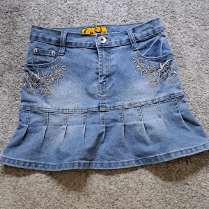 Jeanskjol med broderi - Superfin jeans kjol med guldiga broderier. Köpt på secondhand men inga tecken på andvändning. Skriv gärna vid funderingar!