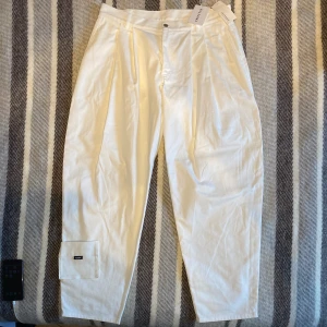 Gosha Rubchinskiy byxor - Gosha Rubchinskiy vita byxor i bomull. Nyskick med tags kvar. Storlek L men sitter stora. 47cm tvärs över, passar bra lite oversized med bälte. 